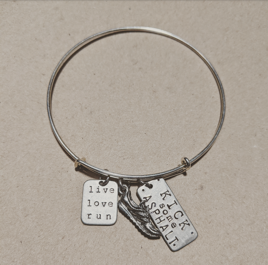 Stainless Steel bracelet with a running shoe charm and a charm that says live, love, run and another charm that says kick some ashphalt