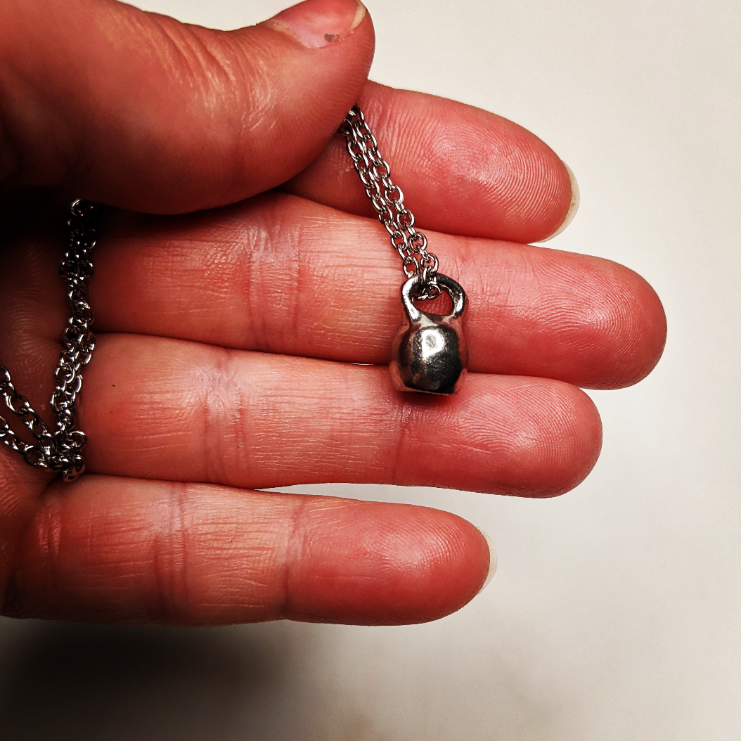 a necklace with a mini kettle bell charm