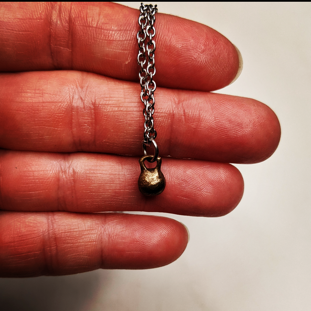 a necklace with a mini kettle bell charm