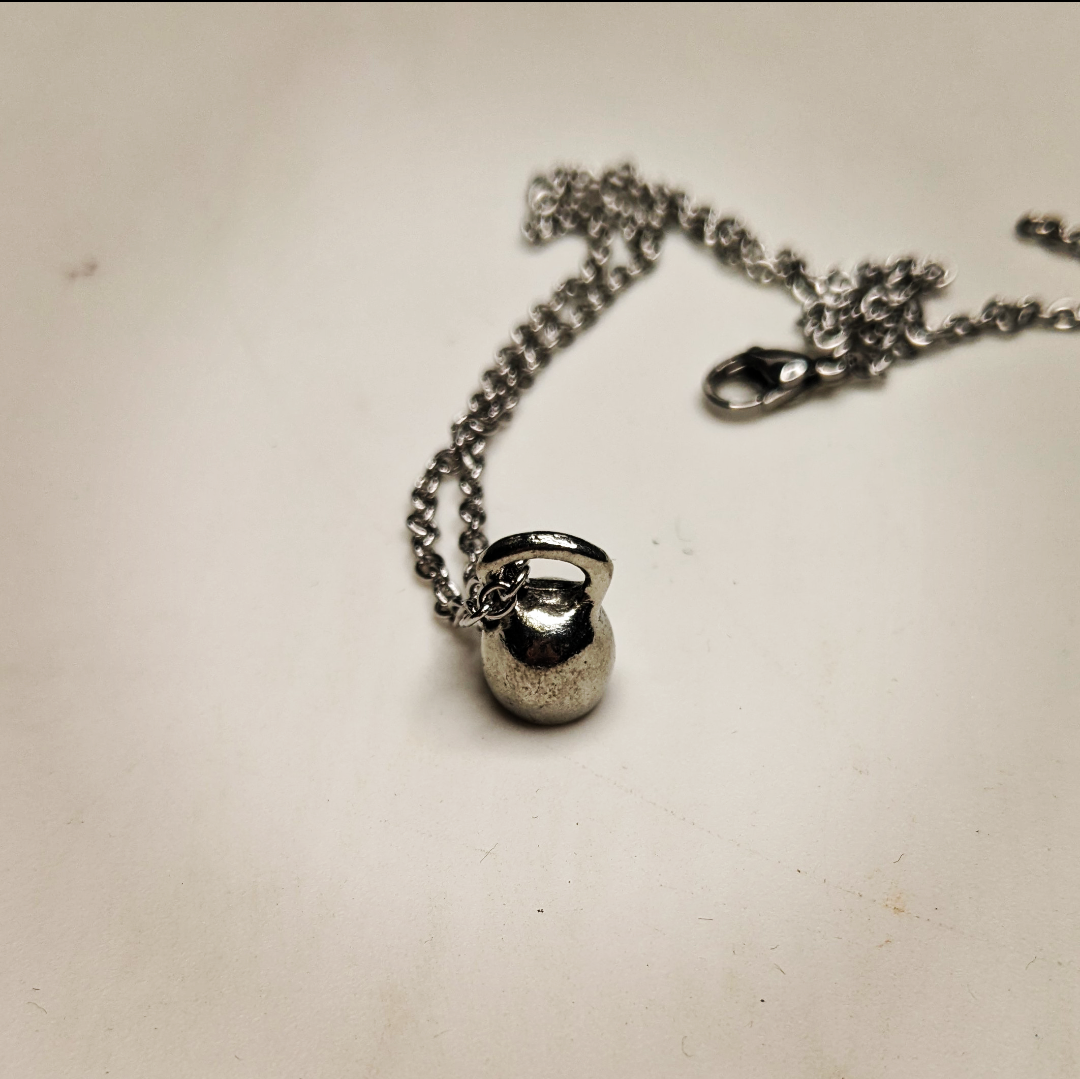 a necklace with a mini kettle bell charm