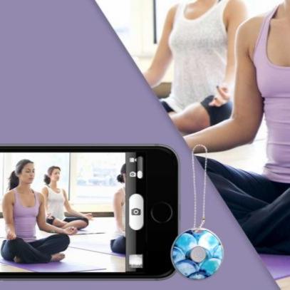 Girl in a yoga class taking a photo from a distance using the Clickie Self Remote technology tool that allows you to take remote photos.