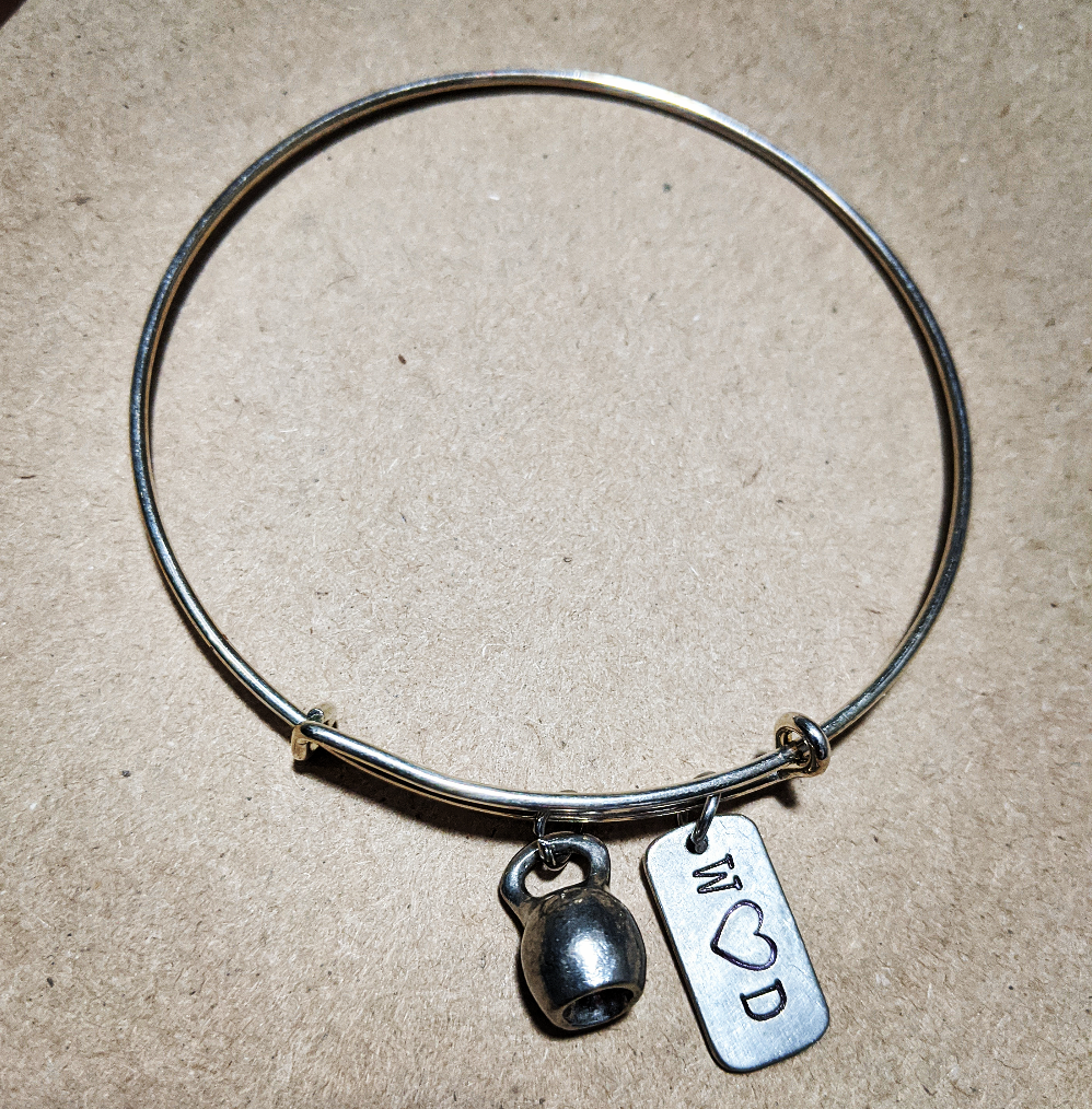 Stainless Steel bracelet with a kettle bell charm and a charm that says W heart D on it.