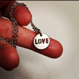 a necklace with a charm that says love on it