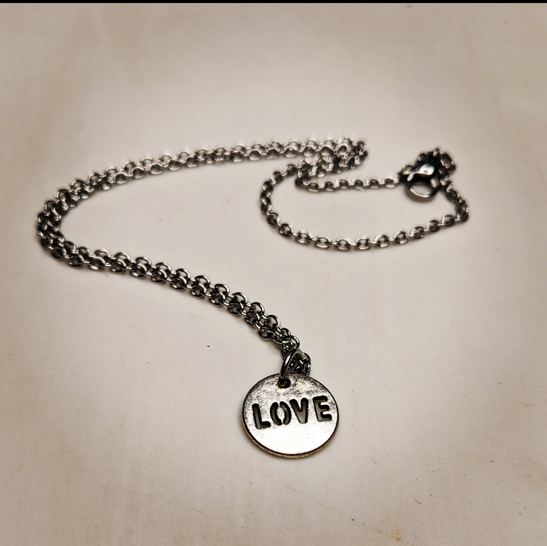 a necklace with a charm that says love on it