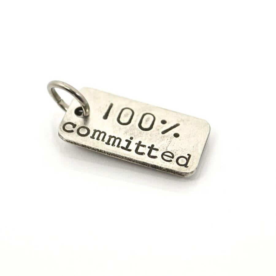 Small stainless steel charm with words 100% committed on it